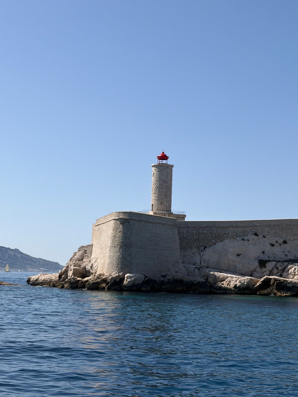Quatre images d'une excursion d'une journée : un enfant assis sur le bastingage d'un bateau avec une casquette regarde un port rempli de voiliers ; une eau cristalline le long d'une côte rocheuse avec des fortifications anciennes ; un phare sur une île rocheuse dans une eau claire.