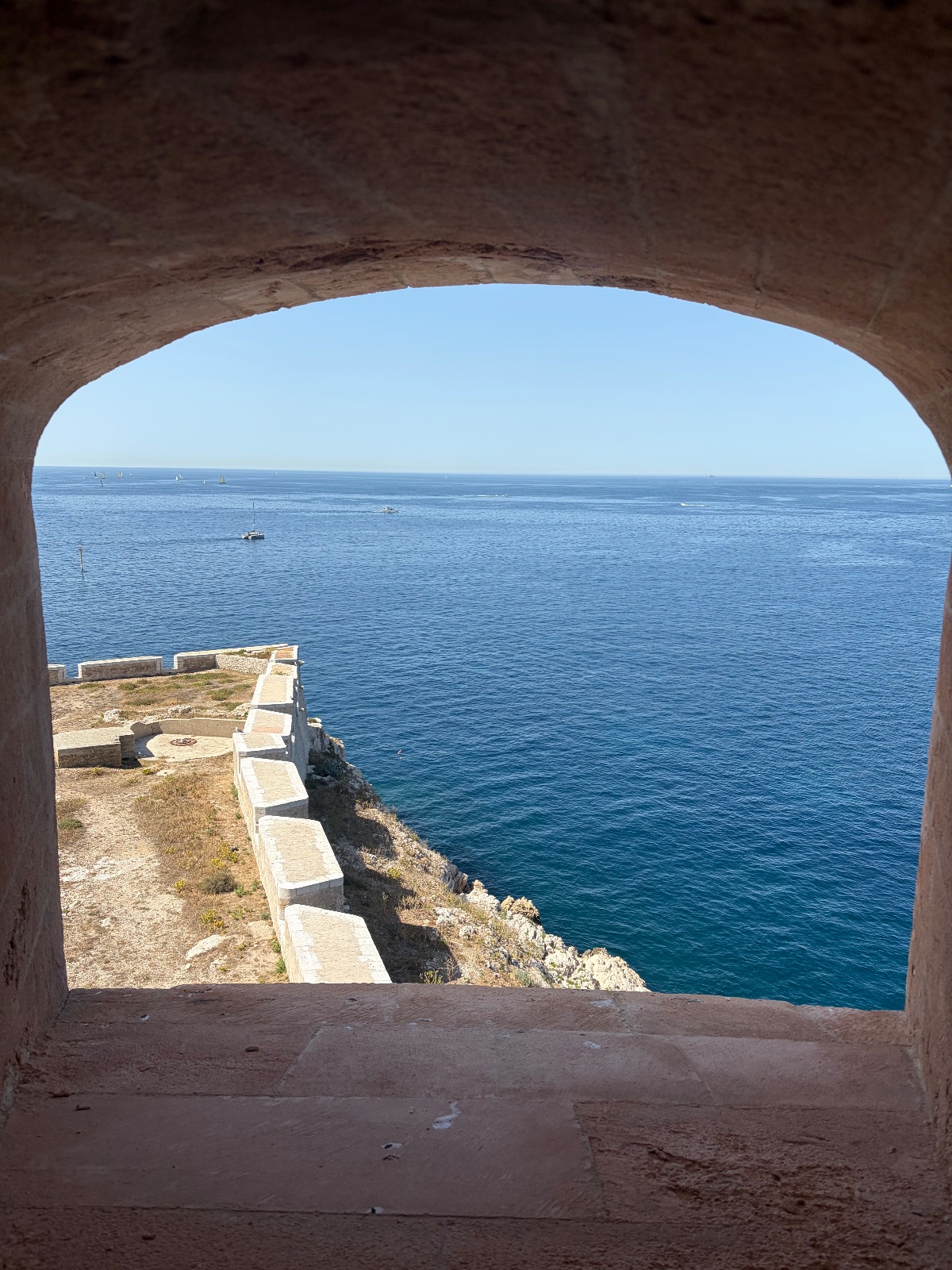 Quatre images d'une excursion d'une journée : un enfant assis sur le bastingage d'un bateau avec une casquette regarde un port rempli de voiliers ; une eau cristalline le long d'une côte rocheuse avec des fortifications anciennes ; un phare sur une île rocheuse dans une eau claire.